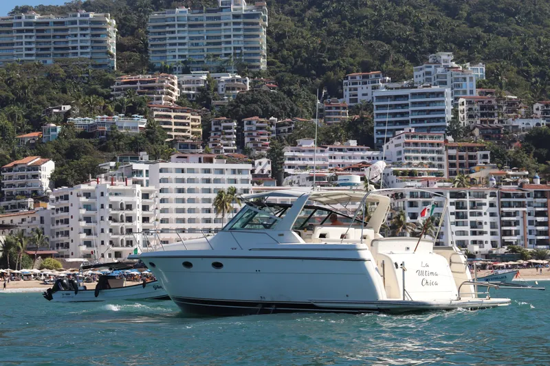 La Ultima Chica Yacht Photos Pics 1997 Tiara Yachts Express cruising near coastal cityscape with hillside buildings.