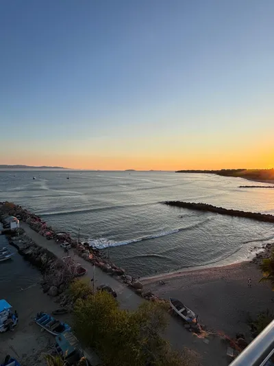 La Ultima Chica Yacht Photos Pics Sunset over a serene coastal view with boats and a 1997 Tiara Yachts Express.