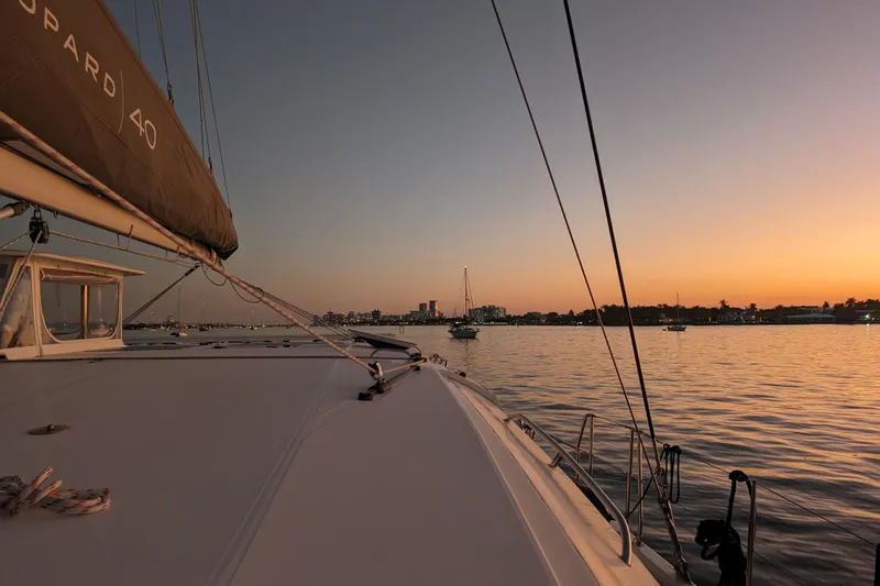 Changing Keys Yacht Photos Pics Leopard 40 catamaran sailing at sunset, calm waters, city skyline in background.