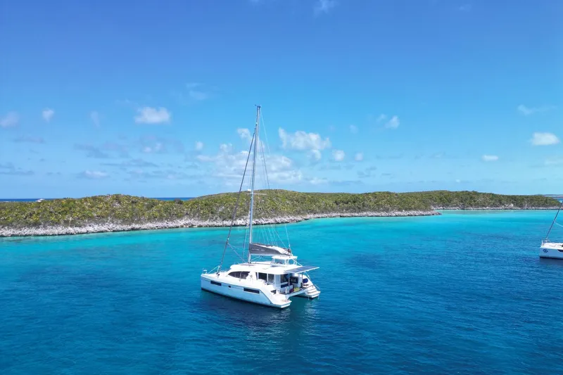 Changing Keys Yacht Photos Pics 2020 Leopard 40 catamaran sailing in clear turquoise waters near a lush island.