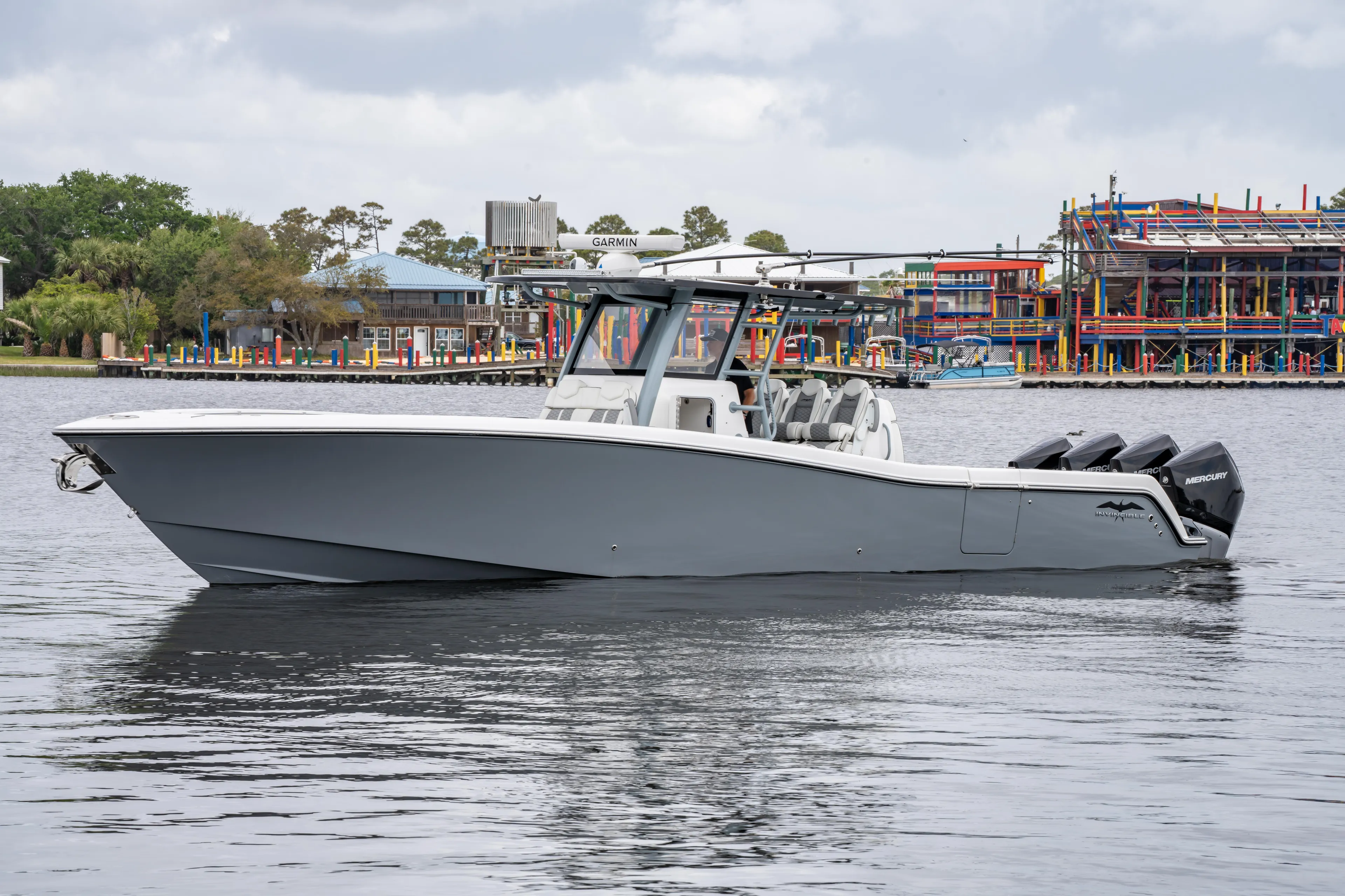  Yacht Photos Pics 2022 Invincible 39 Open Fisherman boat on calm water near colorful waterfront buildings.