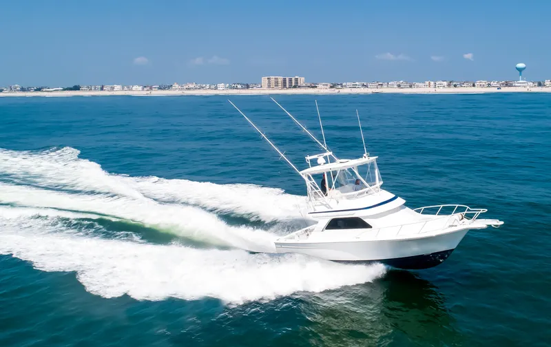  Yacht Photos Pics 2003 Jupiter 35 Flybridge cruising on open water near coastline.