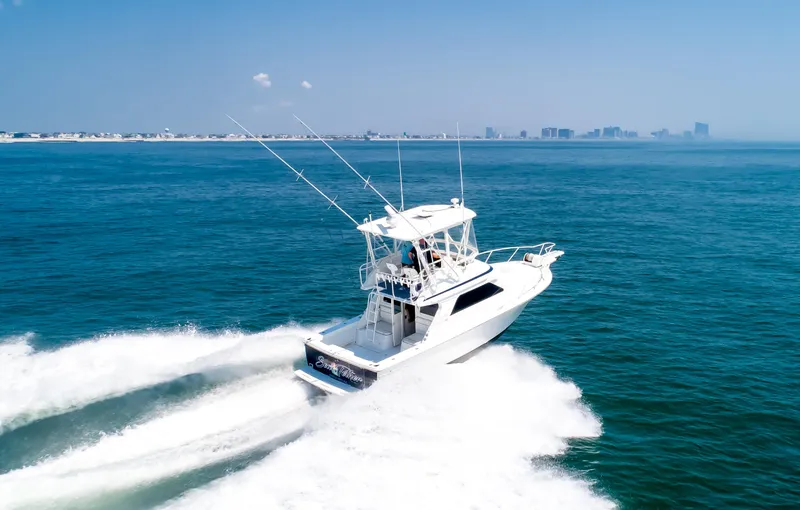  Yacht Photos Pics Jupiter 35 Flybridge 2003 cruising on open sea with city skyline in background.