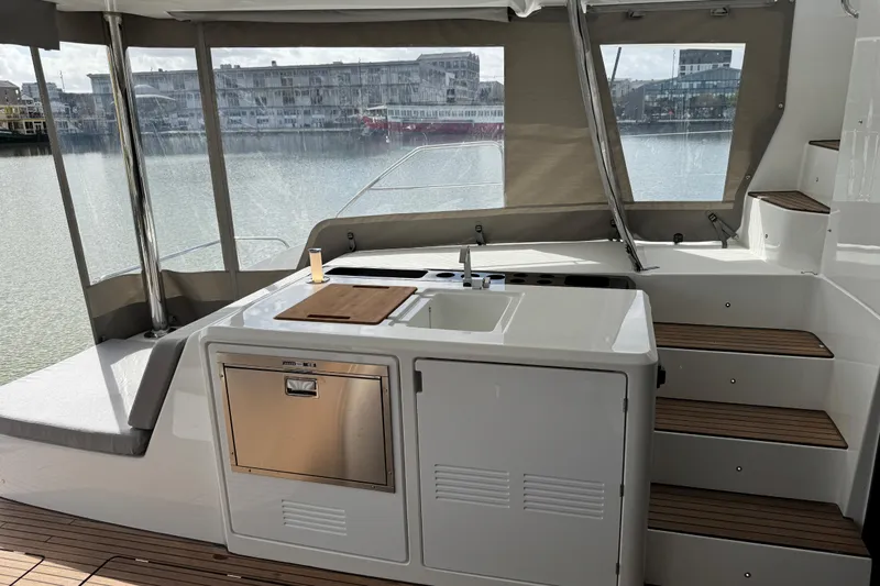  Yacht Photos Pics Outdoor kitchen on 2026 Lagoon 55 yacht with sink, cutting board, and steps.