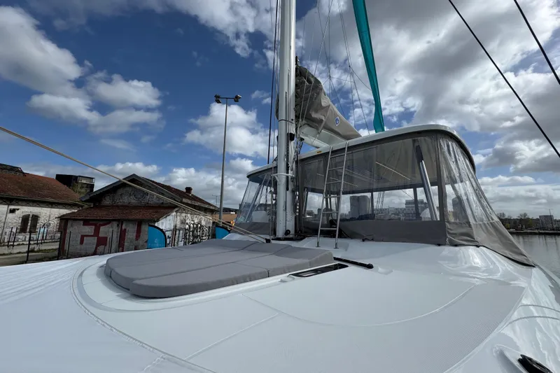  Yacht Photos Pics 2026 Lagoon 55 yacht docked, featuring sleek design and spacious deck under a partly cloudy sky.