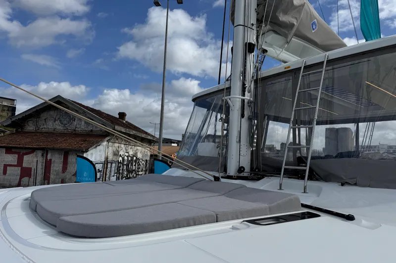  Yacht Photos Pics Luxurious 2026 Lagoon 55 yacht with sunbathing area, docked under a cloudy sky.