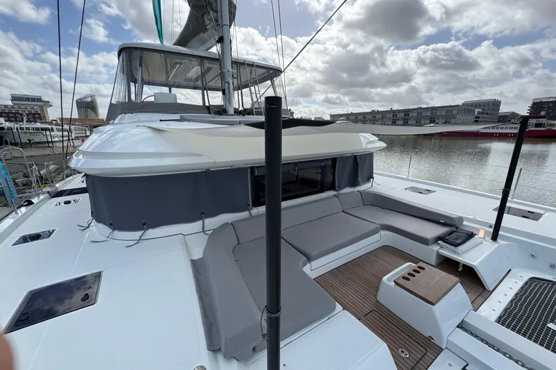  Yacht Photos Pics 2026 Lagoon 55 yacht with spacious deck and modern seating, docked in a marina.