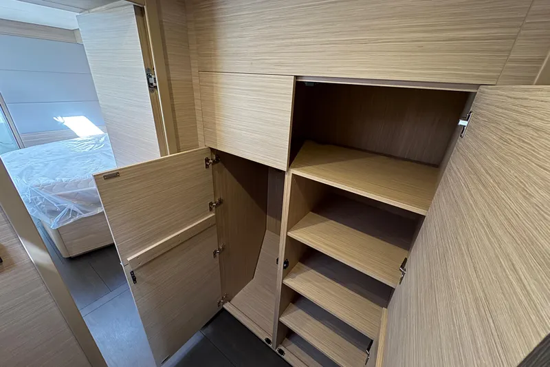  Yacht Photos Pics Interior of 2026 Lagoon 55 yacht showing open wooden storage cabinets and shelves.