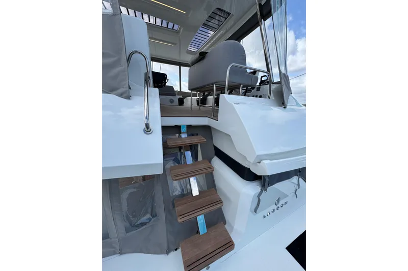  Yacht Photos Pics 2026 Lagoon 55 yacht with wooden steps and modern seating area.