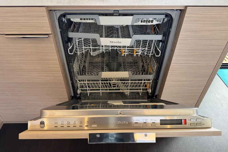  Yacht Photos Pics Open Miele dishwasher in modern kitchen, showcasing interior racks and control panel.