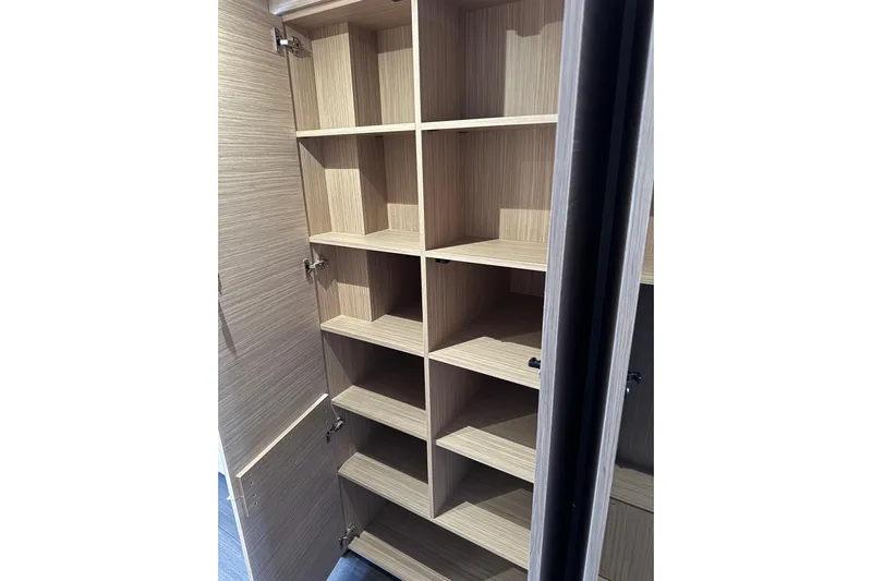  Yacht Photos Pics Open wooden cabinet with multiple shelves in a 2026 Lagoon 55 model.