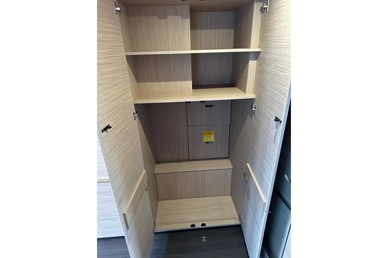  Yacht Photos Pics Open wooden cabinet with shelves inside a 2026 Lagoon 55 yacht.