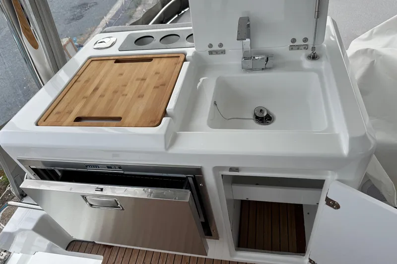  Yacht Photos Pics Modern kitchen area on 2026 Lagoon 55 yacht with sink, cutting board, and storage.