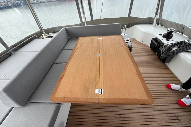  Yacht Photos Pics Spacious deck seating on 2026 Lagoon 55 yacht with wooden table and gray cushions.