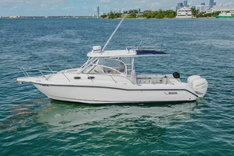  Yacht Photos Pics 2007 Boston Whaler 305 Conquest boat on calm water with city skyline background.