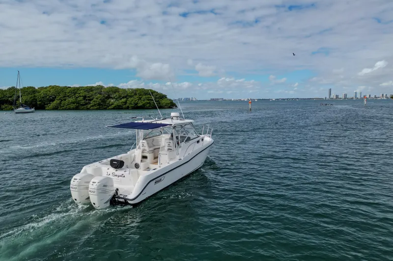  Yacht Photos Pics 2007 Boston Whaler 305 Conquest cruising on a scenic waterway under a partly cloudy sky.