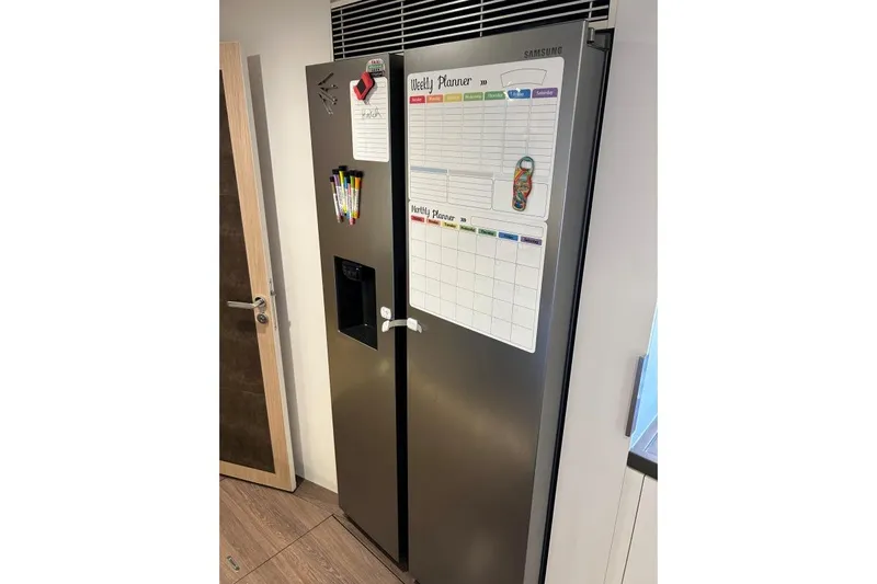 Maty Yacht Photos Pics Samsung refrigerator with weekly planner and markers, in a modern kitchen setting.