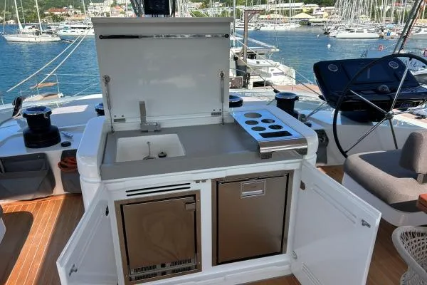 Maty Yacht Photos Pics Outdoor kitchen on 2023 Lagoon Seventy 7 yacht with sink and stove, docked at marina.