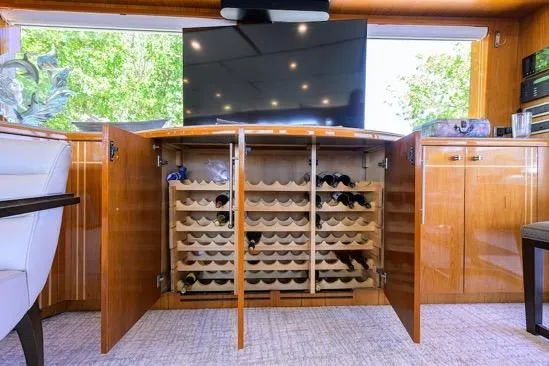 Pomboo Yacht Photos Pics Luxurious 1998 Hatteras 70 yacht interior with wine storage and modern TV setup.