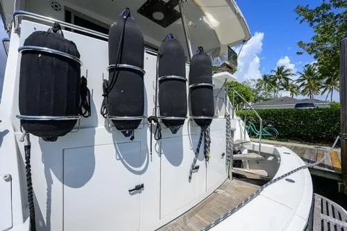 Pomboo Yacht Photos Pics 1998 Hatteras 70 Cockpit Motor Yacht with fenders, docked under clear blue sky.