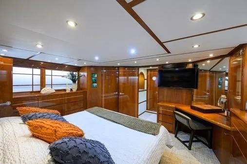 Pomboo Yacht Photos Pics Luxurious bedroom interior of 1998 Hatteras 70 Cockpit Motor Yacht with wood paneling and modern amenities.
