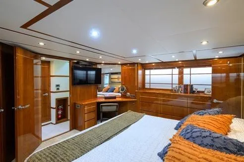Pomboo Yacht Photos Pics Luxurious interior of 1998 Hatteras 70 Cockpit Motor Yacht bedroom with wood paneling.