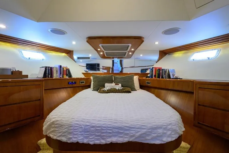 Pomboo Yacht Photos Pics Luxurious cabin interior of 1998 Hatteras 70 Cockpit Motor Yacht with cozy bed and wooden accents.