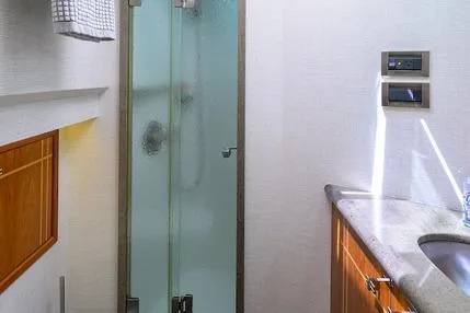 Pomboo Yacht Photos Pics 1998 Hatteras 70 Cockpit Motor Yacht bathroom with glass shower and wooden cabinetry.