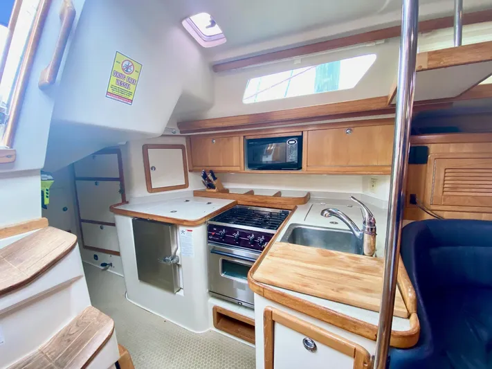Licentia Yacht Photos Pics 2008 Catalina 42 MkII yacht kitchen with wood cabinetry, stove, sink, and microwave.
