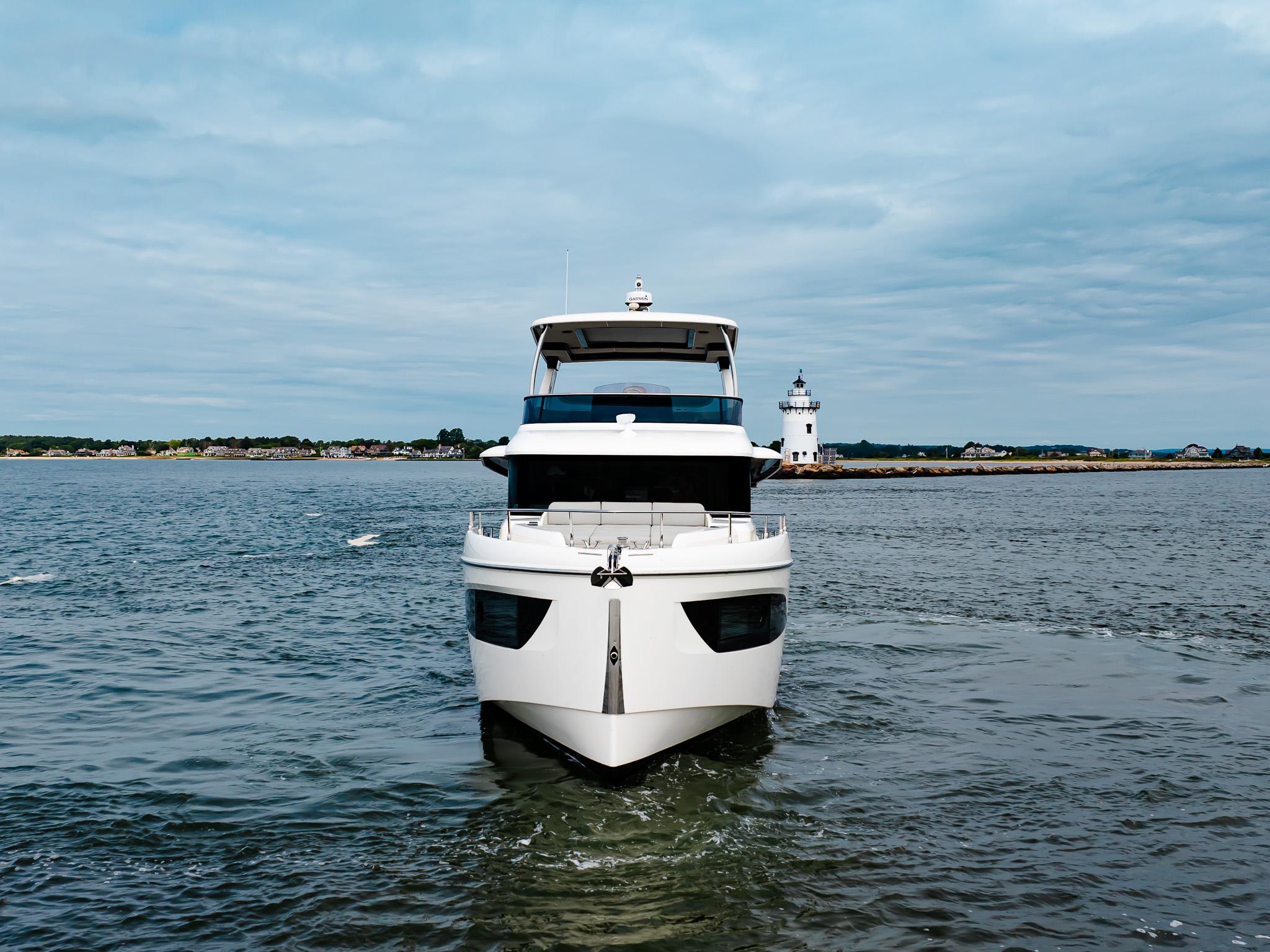 2023 Absolute 52 Navetta yacht cruising near a lighthouse on a cloudy day.