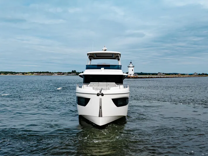 The Transporter Yacht Photos Pics 2023 Absolute 52 Navetta yacht cruising near a lighthouse on a cloudy day.