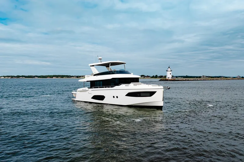 The Transporter Yacht Photos Pics 2023 Absolute 52 Navetta yacht cruising near a lighthouse on a cloudy day.