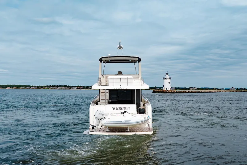 The Transporter Yacht Photos Pics 2023 Absolute 52 Navetta yacht cruising near a lighthouse on a calm sea.