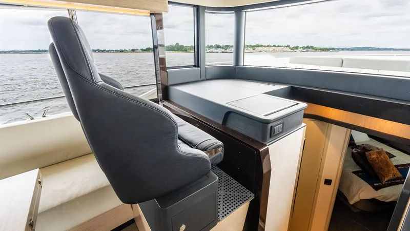 The Transporter Yacht Photos Pics Pilot seat and helm station on 2023 Absolute 52 Navetta yacht, overlooking serene waters.