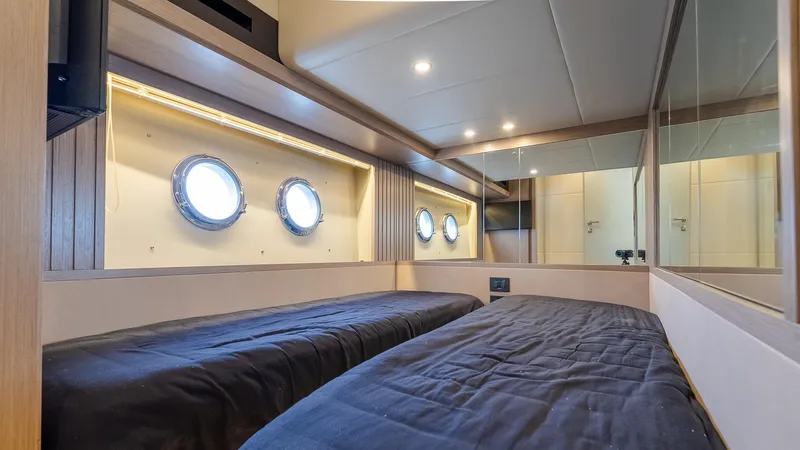 The Transporter Yacht Photos Pics Luxurious twin cabin interior on 2023 Absolute 52 Navetta yacht with porthole windows.