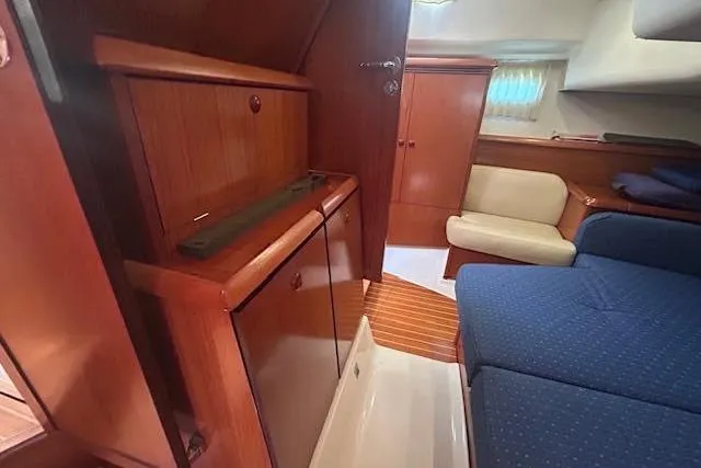 Nonna Yacht Photos Pics Interior of 2005 Jeanneau Deck Salon 43, featuring wooden cabinetry and blue seating.