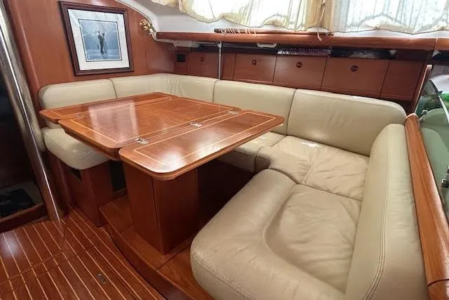 Nonna Yacht Photos Pics Interior of 2005 Jeanneau Deck Salon 43 with wooden table and beige leather seating.