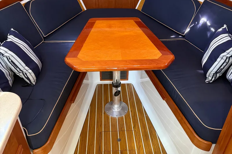 Eventide Yacht Photos Pics 2007 Back Cove 29 interior with wooden table, navy cushions, and striped pillows.