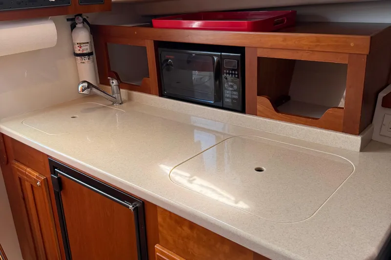Eventide Yacht Photos Pics 2007 Back Cove 29 boat kitchen with sink, microwave, and wooden cabinetry.