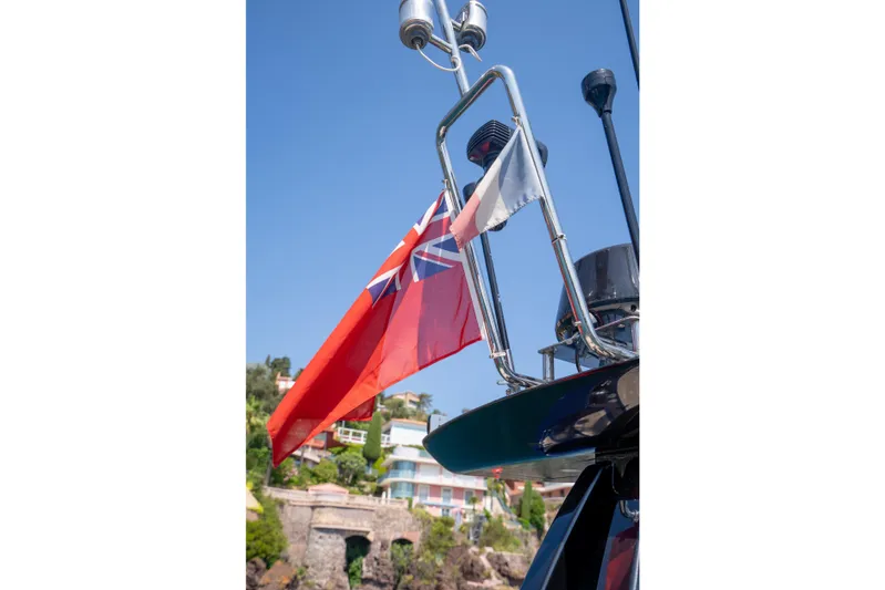  Yacht Photos Pics 2015 Riva 63 Virtus yacht with flags, coastal backdrop, clear blue sky.