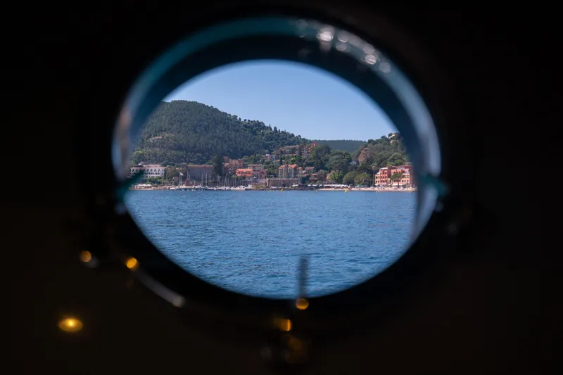  Yacht Photos Pics Porthole view from 2015 Riva 63 Virtus yacht, showcasing scenic coastal landscape.