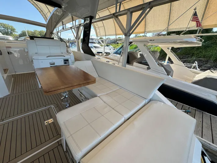 Yacht Rock Yacht Photos Pics 2015 Cruisers Yachts 390 Express Coupe interior with seating and table, docked under canopy.