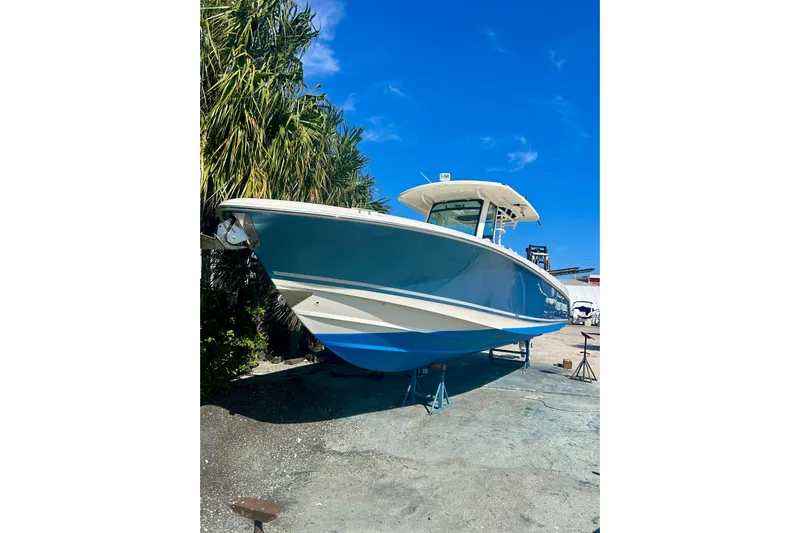 Overtime Yacht Photos Pics 2018 Boston Whaler 330 Outrage boat on land, clear blue sky background.