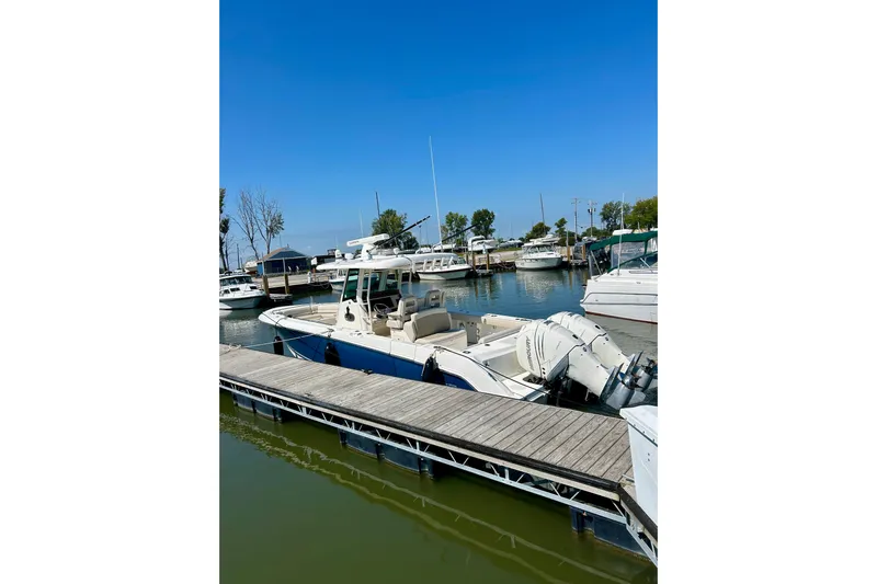 Overtime Yacht Photos Pics 2018 Boston Whaler 330 Outrage docked at a marina under clear blue skies.