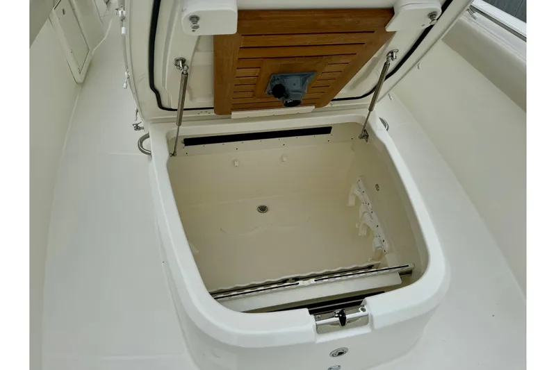 Overtime Yacht Photos Pics 2018 Boston Whaler 330 Outrage storage compartment with open hatch and wooden lid.