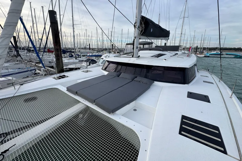 Lupa Di Mare Yacht Photos Pics 2021 Fountaine Pajot Saona 47 catamaran docked in a marina, featuring spacious deck and netting.