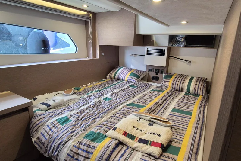 Ker Lann Yacht Photos Pics Luxurious 2022 Prestige 460 yacht cabin with striped bedding and modern amenities.