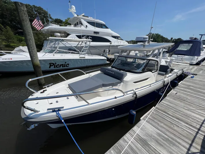 Chill Yacht Photos Pics Nimbus T8 2025 boat docked at marina, surrounded by other vessels under clear blue sky.