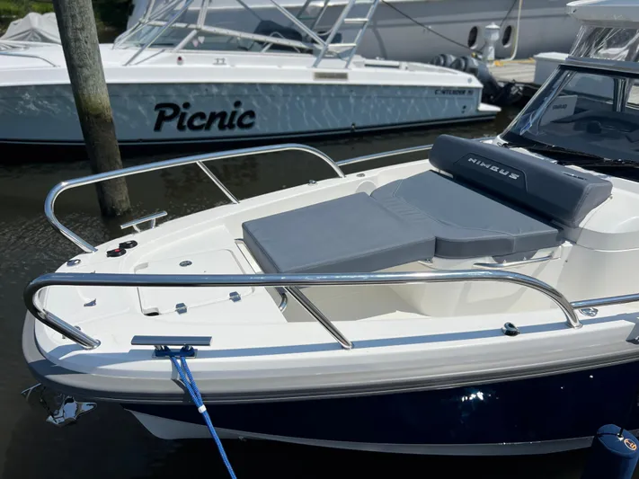 Chill Yacht Photos Pics 2025 Nimbus T8 boat with cushioned seating, docked near another vessel.