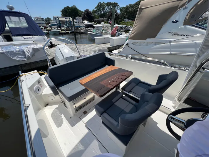 Chill Yacht Photos Pics Luxurious Nimbus T8 boat interior with seating and wooden table, docked at a marina, 2025 model.